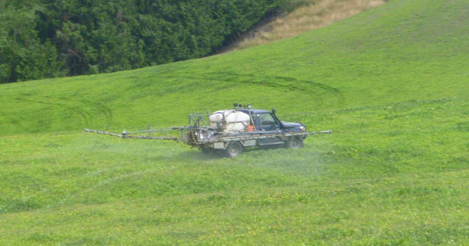 a vehicle spraying onto a grass paddock